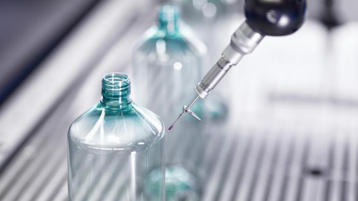Plastic bottle being quality tested by automated machinery in a production facility.