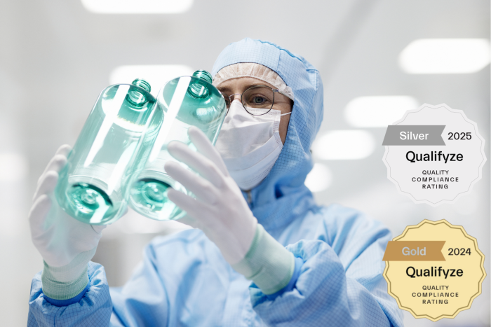 ALPLA technician inspecting plastic bottles in a cleanroom with Qualifyze audit results